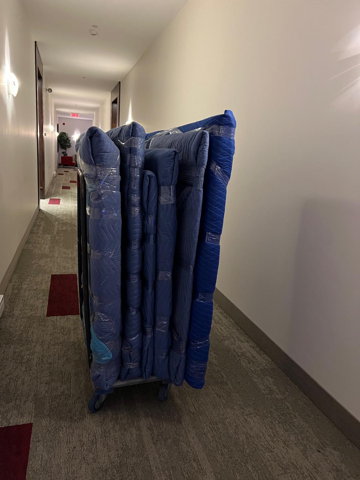 Matelas emballés et sanglés sur un diable dans un corridor