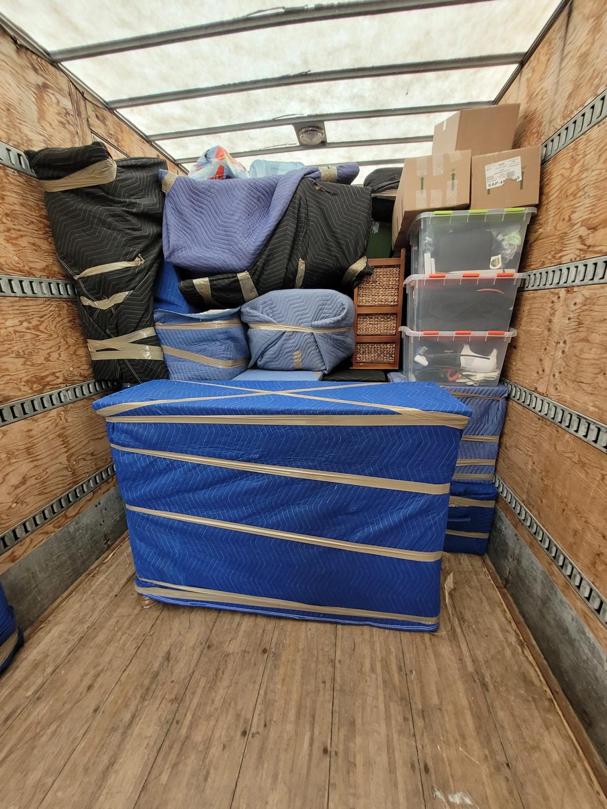 Camion chargé de meubles emballés, de boîtes et de miroirs calés contre la paroi