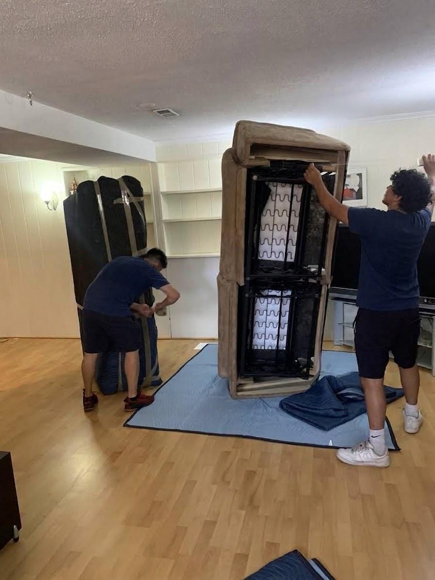 Deux déménageurs déplaçant une grande armoire sur des couvertures posées au sol