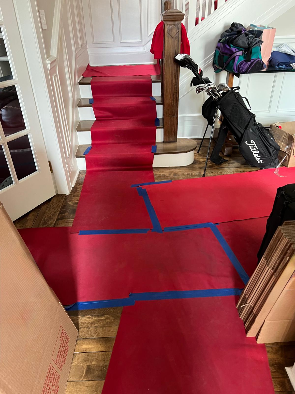 Escalier et entrée protégés par un tapis rouge fixé au ruban