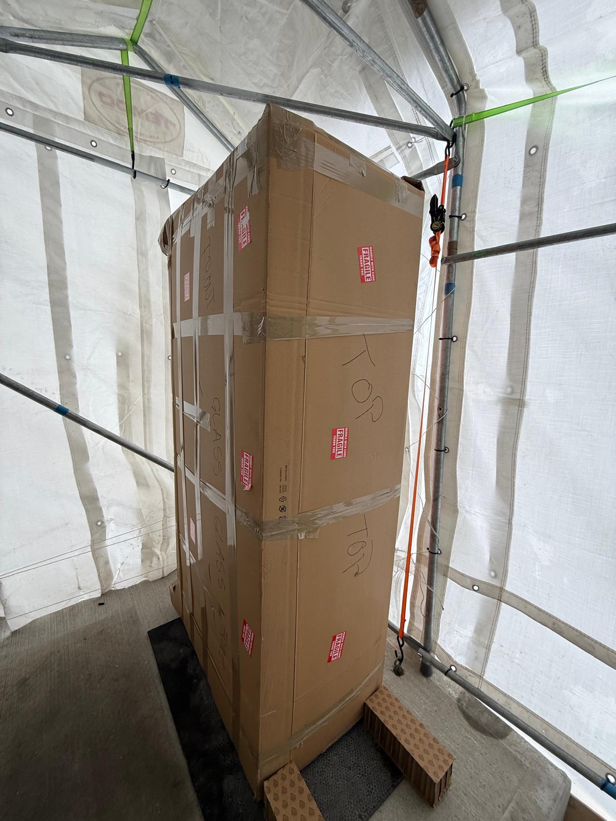 Grand meuble emballé de carton et de pellicule avec des étiquettes Fragile