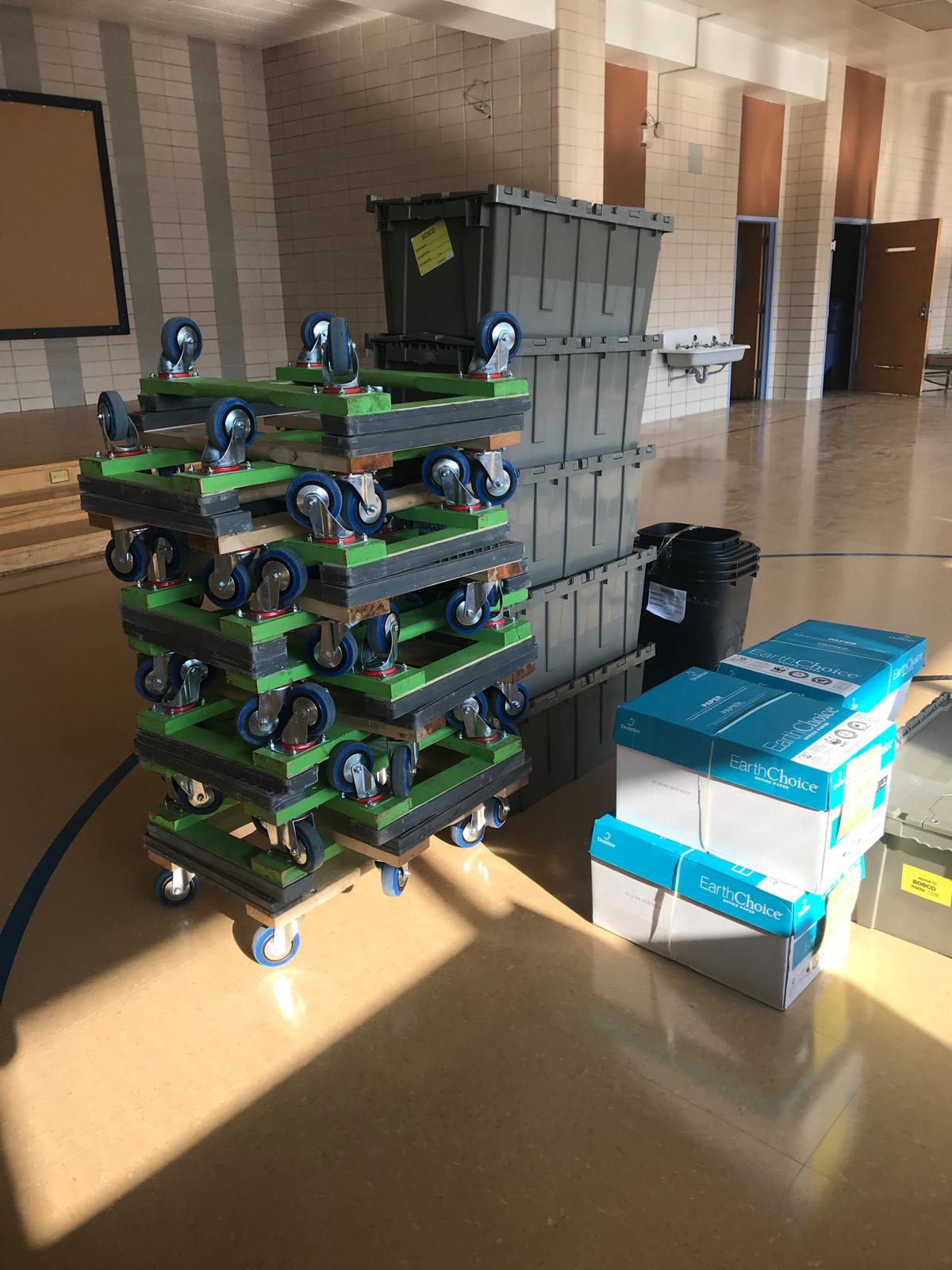 Bacs de plastique réutilisables empilés et étiquetés à côté d'une pile de plateaux roulants, dans un local institutionnel