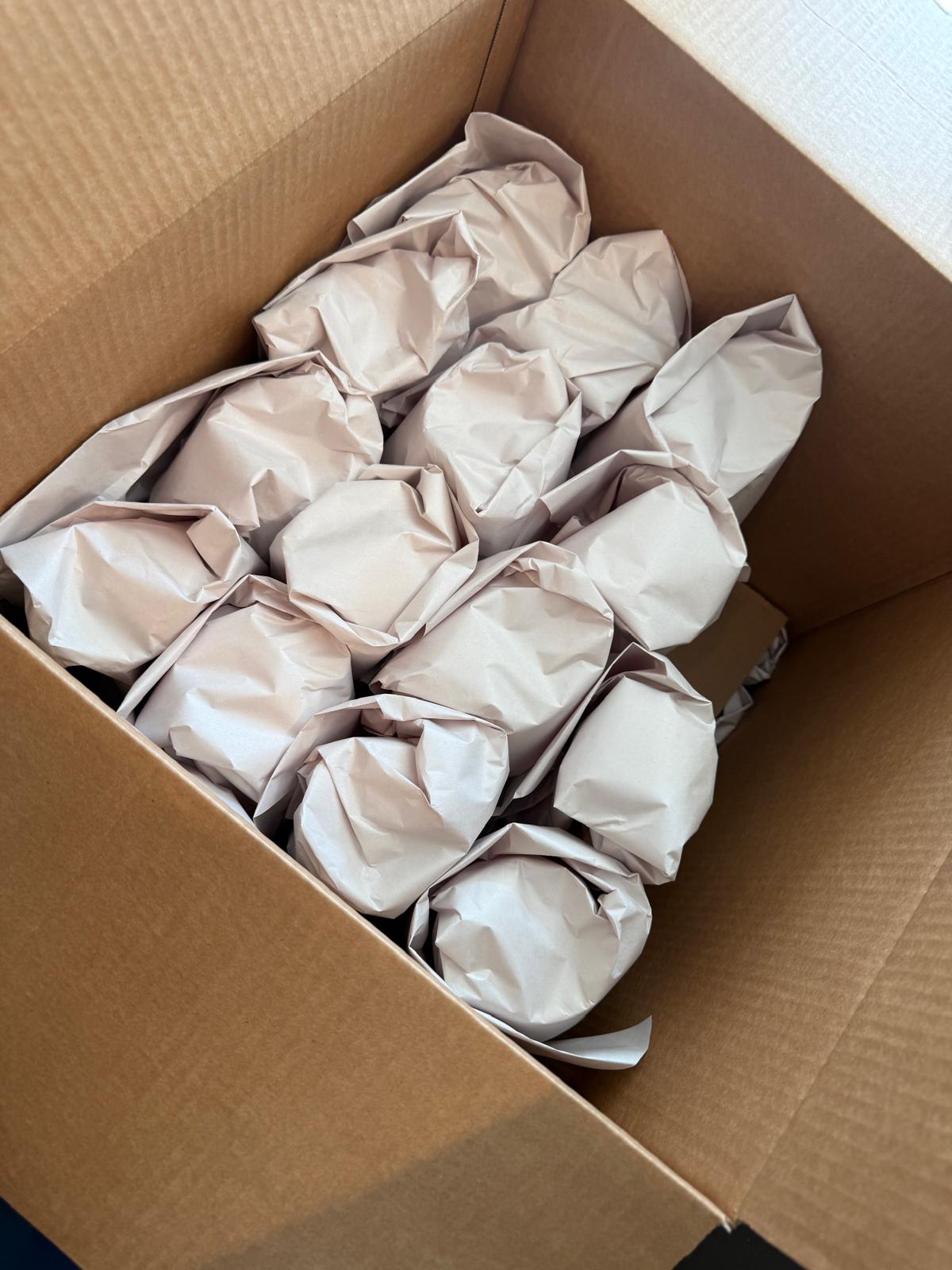 Verres emballés un par un dans du papier et rangés debout dans une boîte de carton