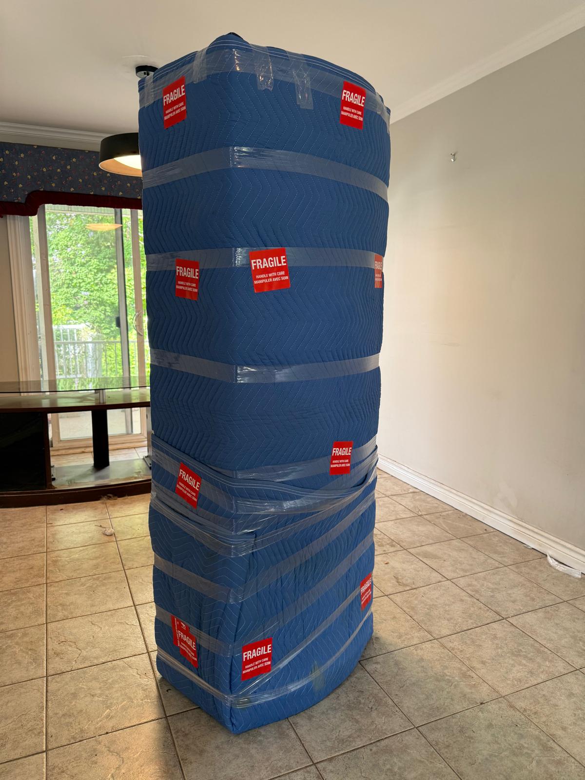 Pile de meubles emballés dans des couvertures matelassées avec des étiquettes Fragile