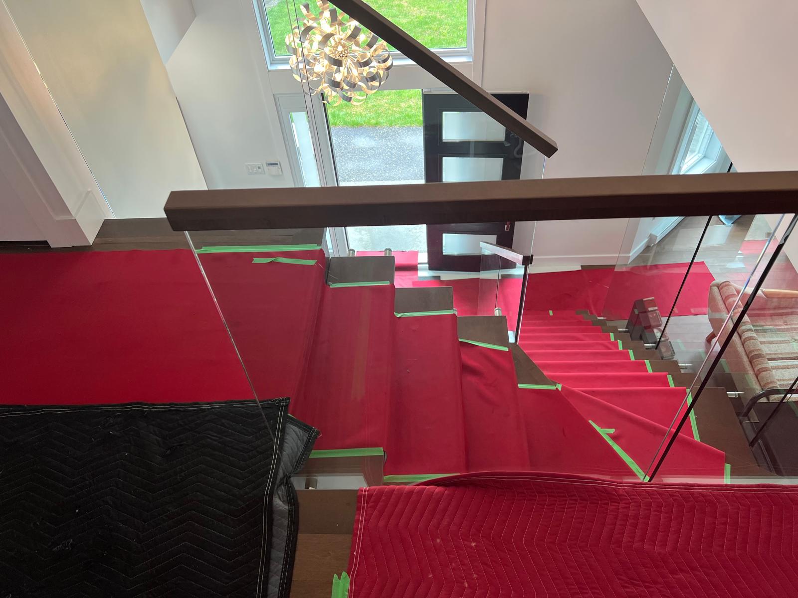 Escalier de maison protégé par un tapis rouge sur toute sa longueur avant le déménagement