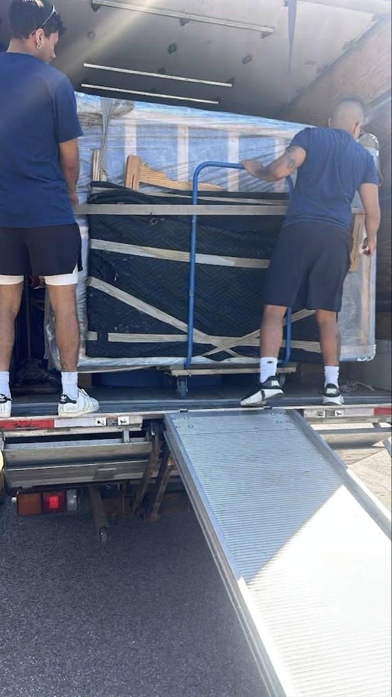 Deux déménageurs montant un meuble emballé dans le camion par la rampe