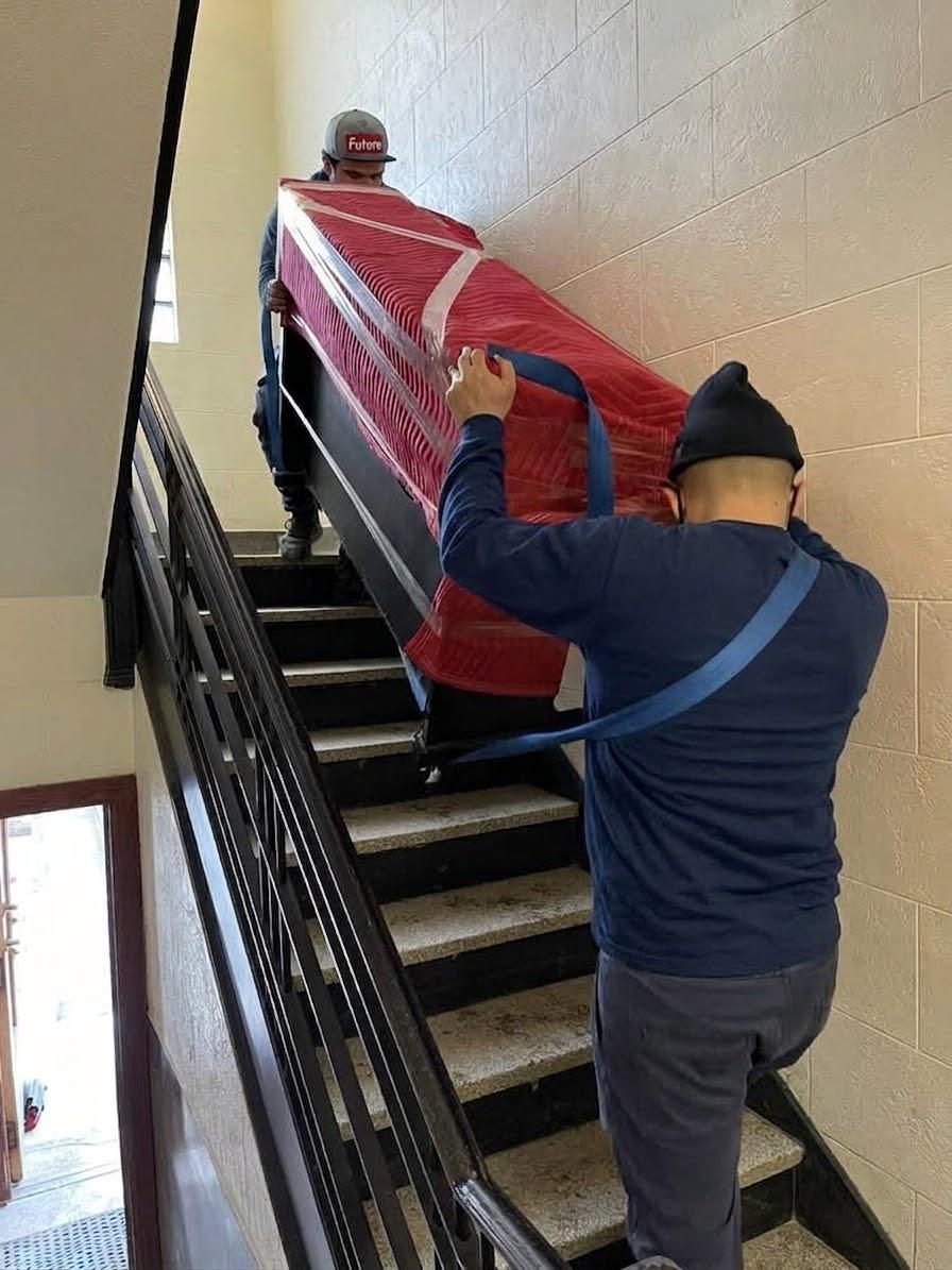 Sofa emballé monté à deux dans un escalier étroit avec l'équipement