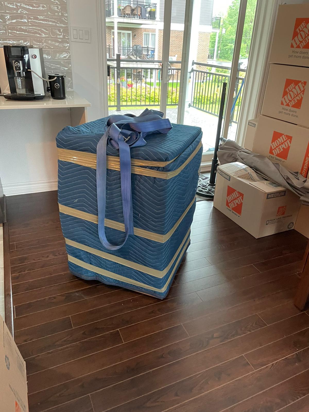 Meuble emballé dans une couverture matelassée avec sangle de portage, prêt à sortir