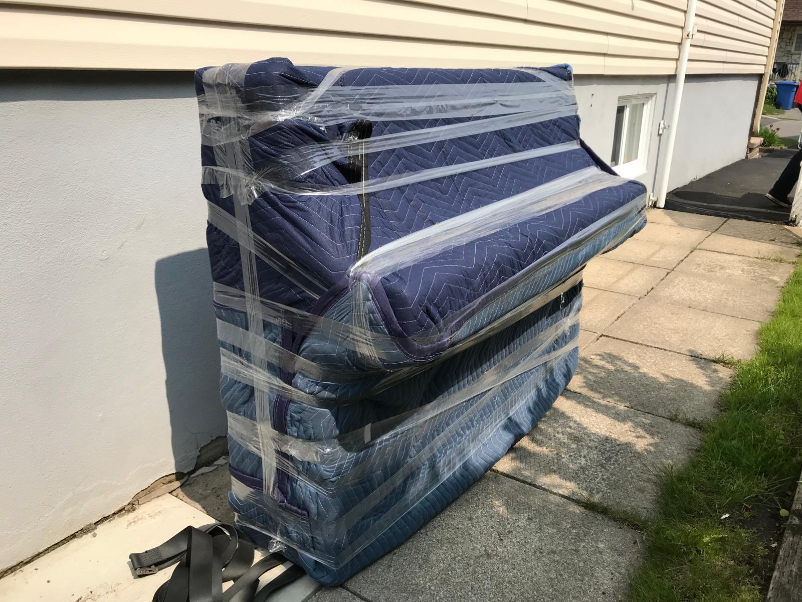 Piano droit emballé et sanglé sur un chariot à l'extérieur d'une maison