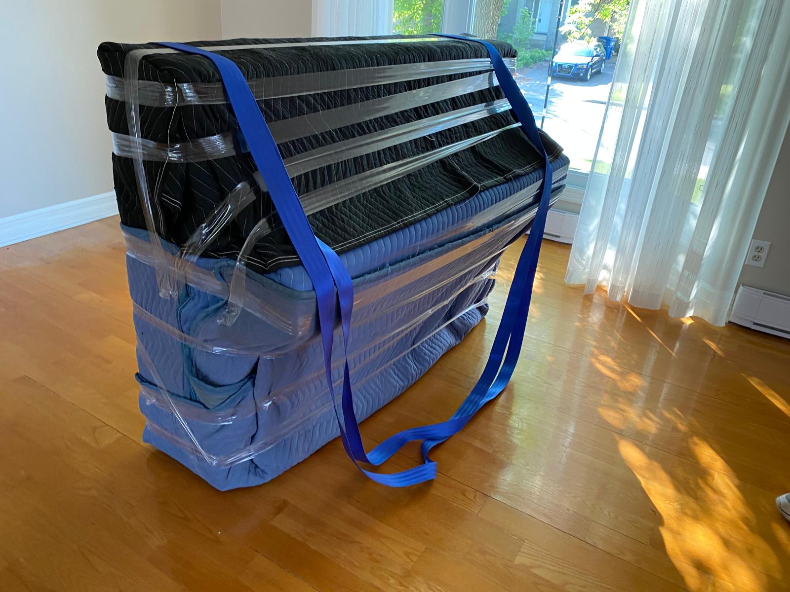 Piano à queue emballé et sanglé avec des sangles bleues dans un salon
