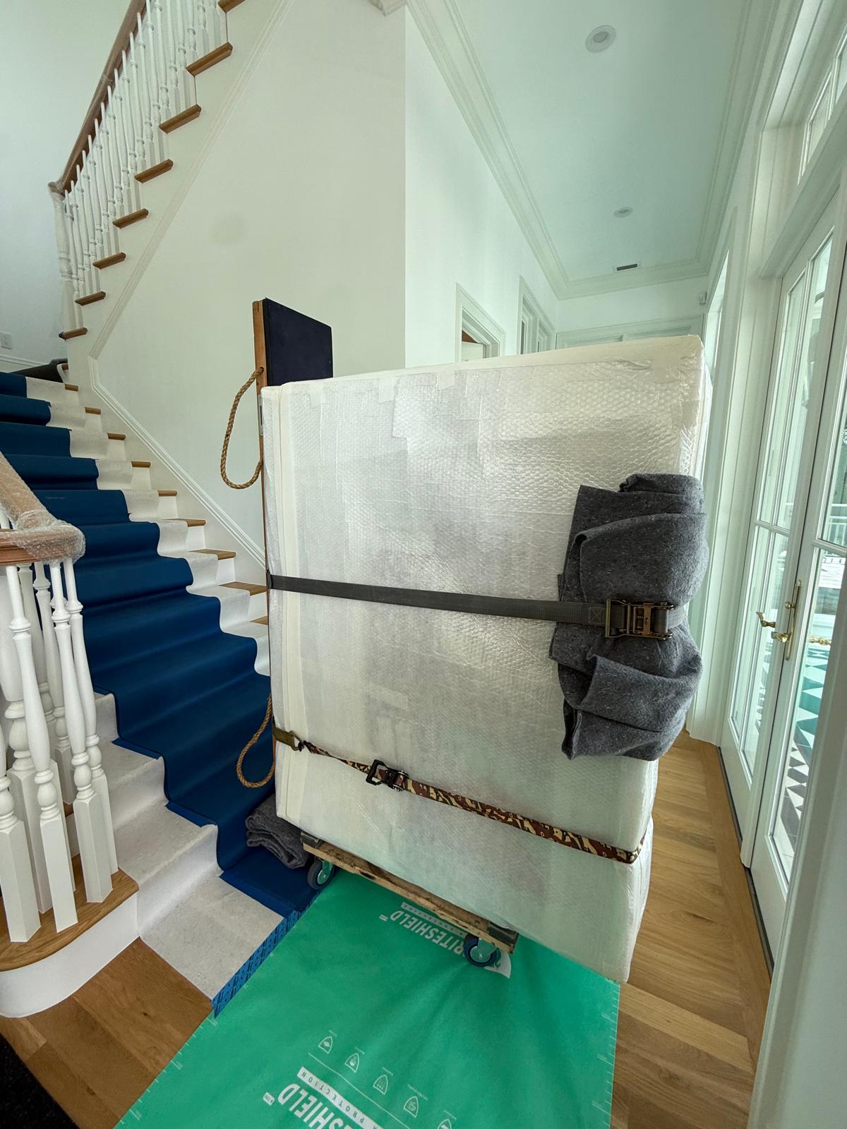 Piano emballé et sanglé au pied d'un escalier intérieur protégé