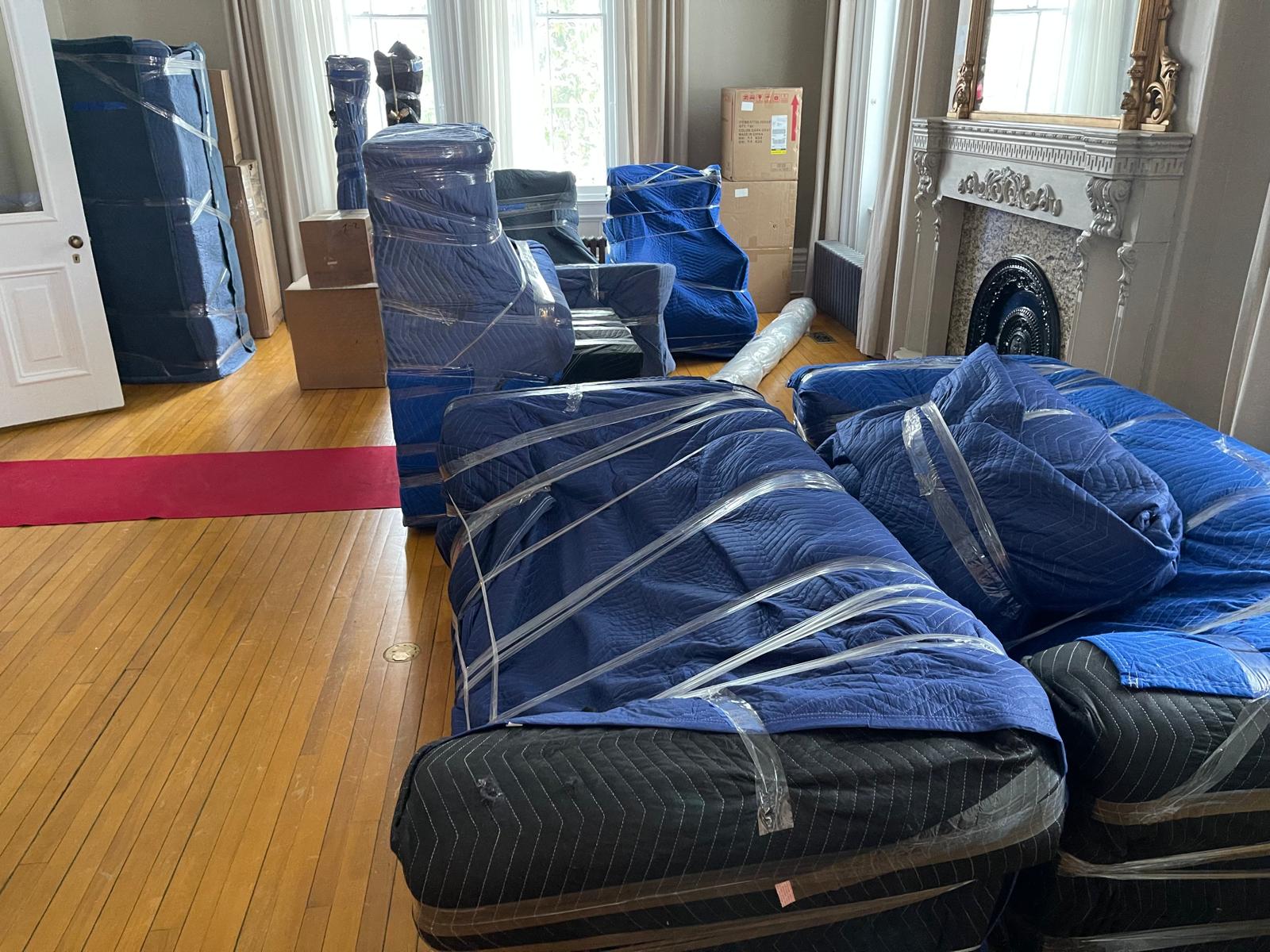 Salon complet dont chaque meuble est emballé dans des couvertures matelassées et de la pellicule