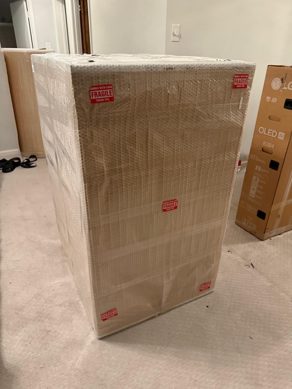 Gros appareil emballé de carton et de pellicule avec des étiquettes Fragile