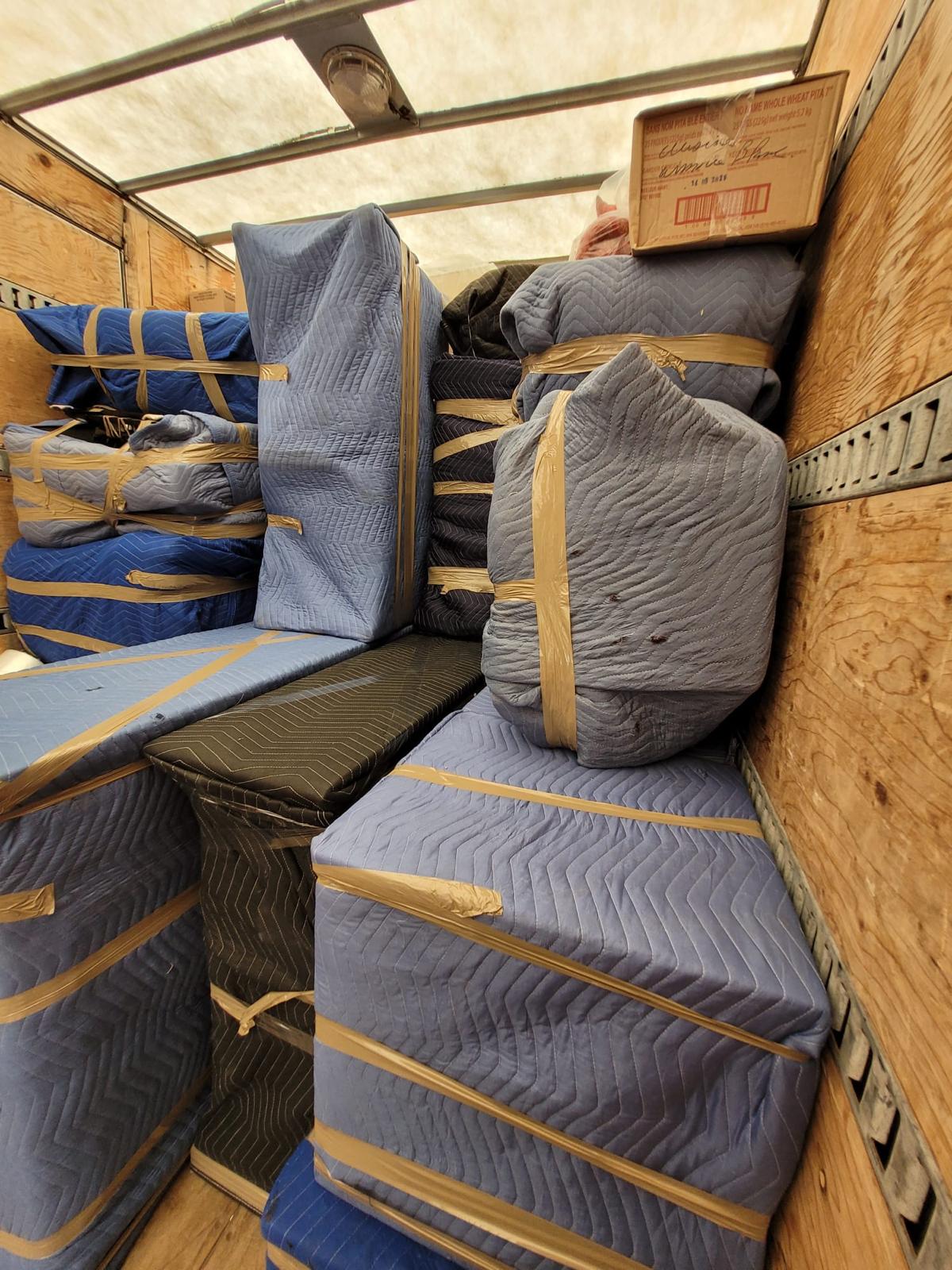 Camion de déménagement chargé : meubles emballés et attachés par sections contre la paroi
