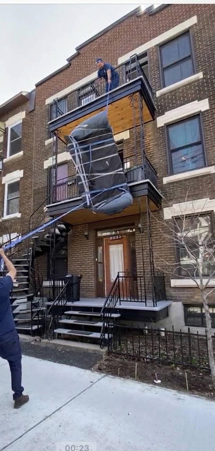 Sofa emballé et descendu par le balcon d'un deuxième étage avec des sangles, un déménageur en haut et un autre au sol