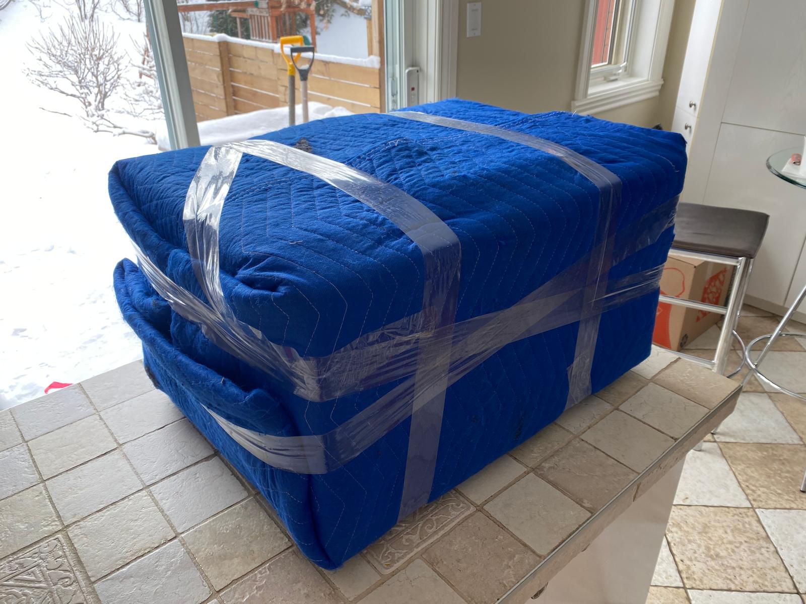 Meuble emballé dans une couverture matelassée et de la pellicule, prêt à sortir par la porte-patio en hiver
