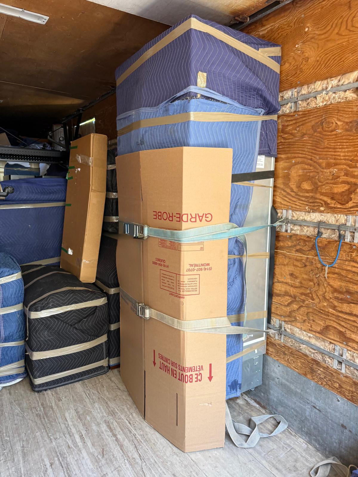 Boîte garde-robe et matelas emballés, sanglés contre la paroi du camion