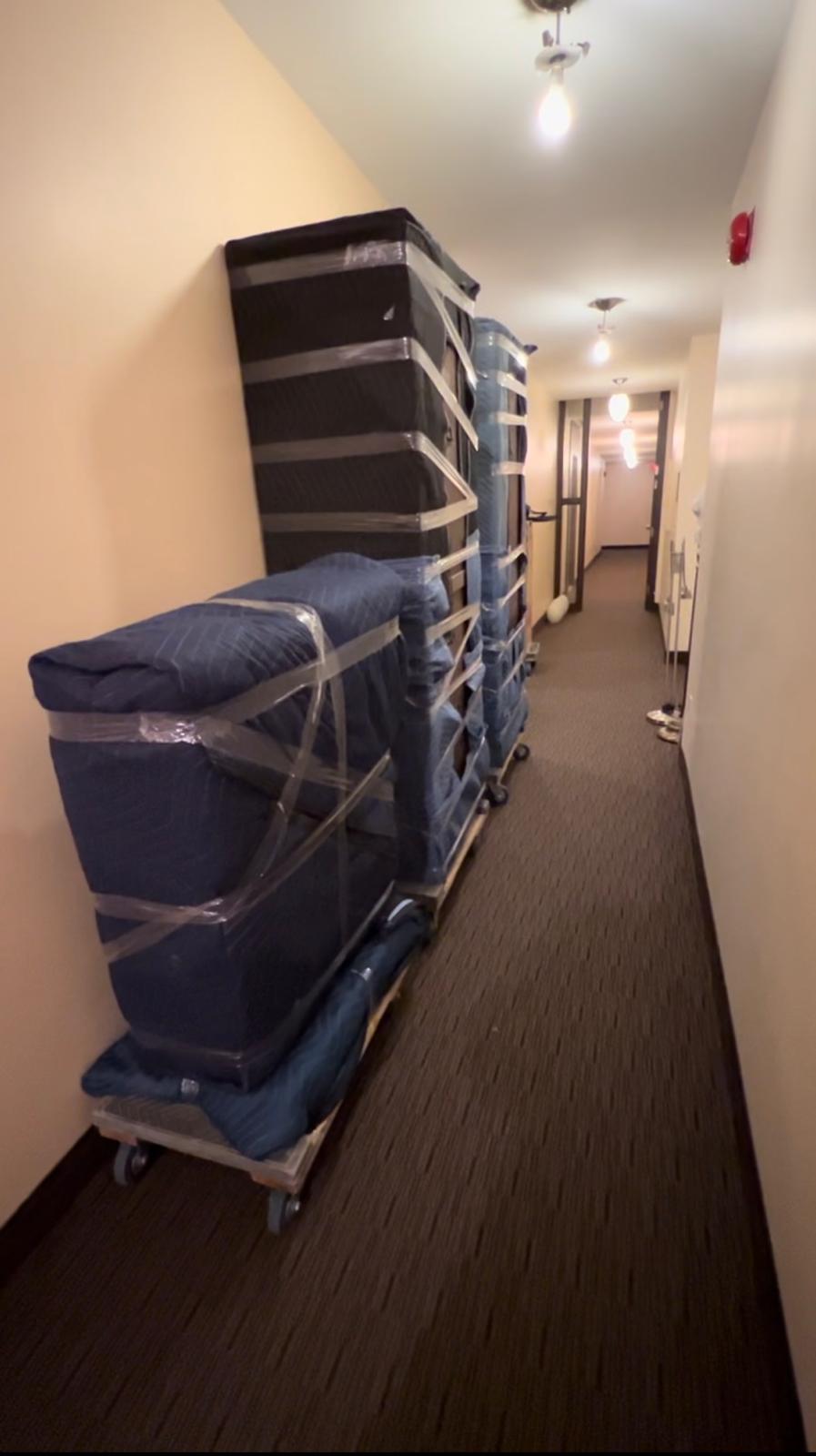 Matelas et meubles emballés empilés sur un diable dans un couloir