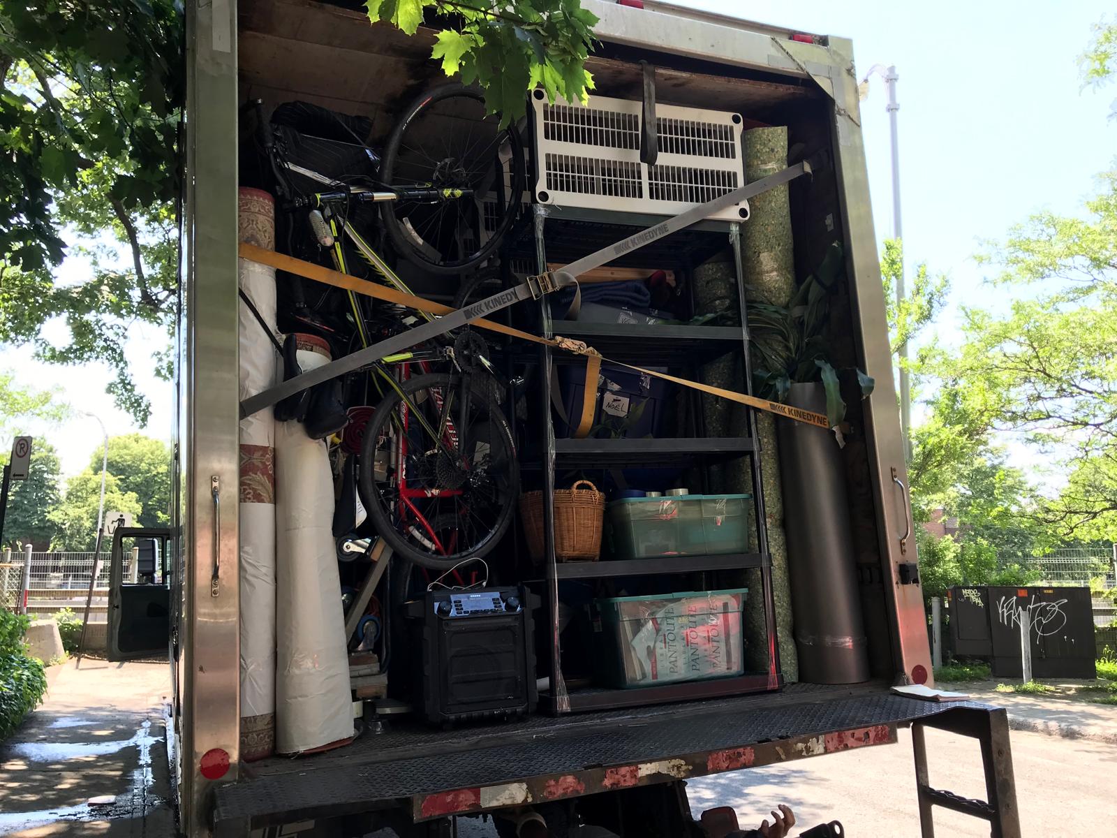 Camion chargé du contenu d'un garage : vélos, étagères, outils et matériel de jardin